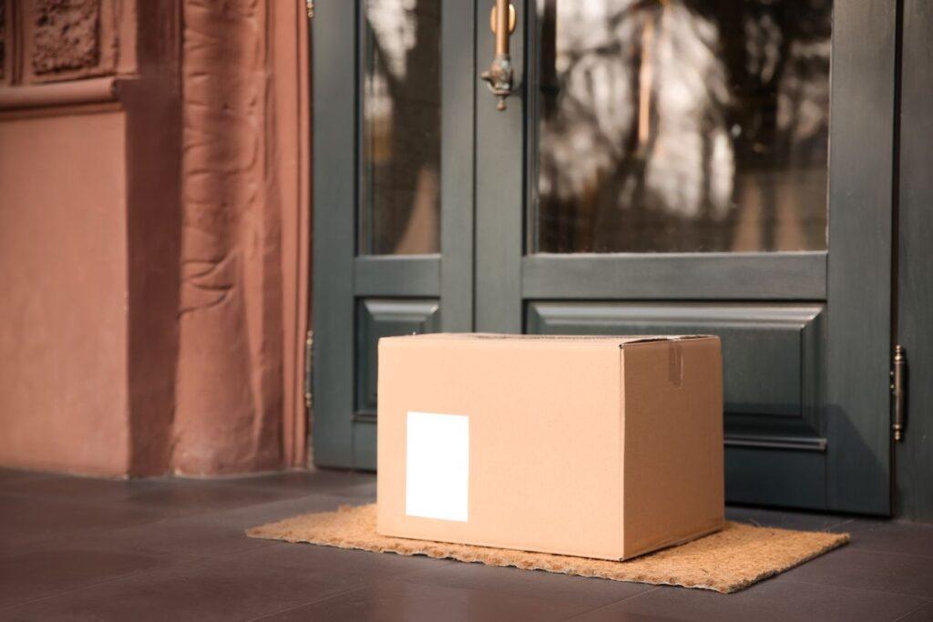 Paket auf Fußmatte vor Haustuer – ein Paketkasten verhindert unsichere Ablagen und schuetzt Lieferungen